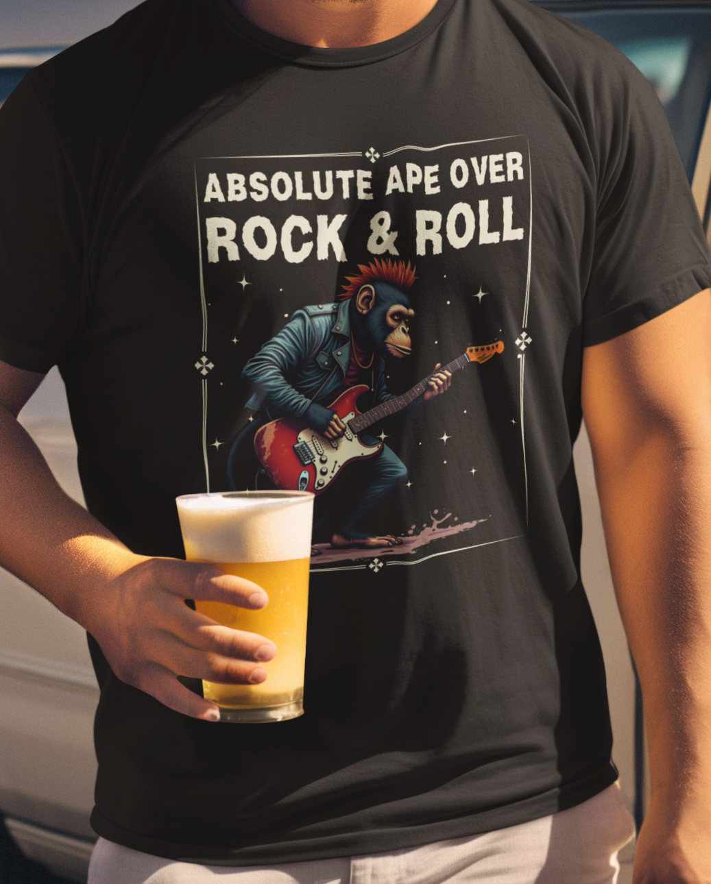 Person wearing a black t-shirt with a graphic of an ape playing guitar and text 'Absolute Ape Over Rock & Roll', holding a beer.